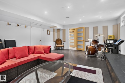 Lower-level recreation space featuring dark flooring, recessed lighting, sound-dampening wall panels, and light wood interior doors with frosted glass panels - 5808 Austin O'Brien Road, Edmonton, AB 