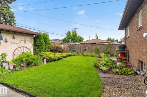 Expansive green lawn bordered by established landscaping, a gravel pathway, and a privacy fence - 5808 Austin O'Brien Road, Edmonton, AB 