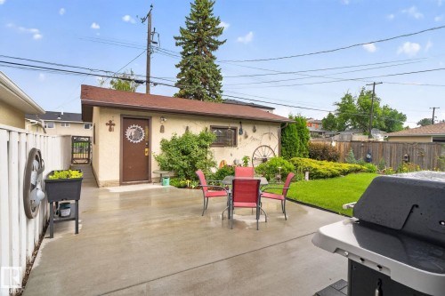 Concrete patio area featuring a detached structure with a brown door and a side gate entry - 5808 Austin O'Brien Road, Edmonton, AB 