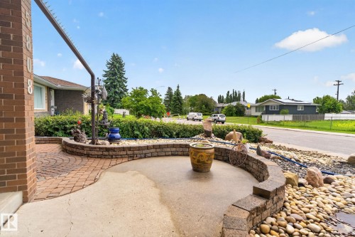 Exterior entrance featuring brick detailing, a paver pathway, and a curved concrete patio - 5808 Austin O'Brien Road, Edmonton, AB 