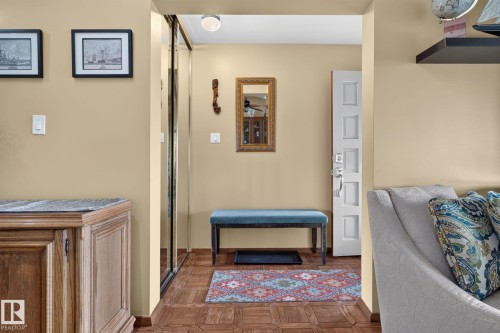 Entryway with wood-finish parquet flooring, a white paneled door, and a full-height mirrored closet - 5808 Austin O'Brien Road, Edmonton, AB 