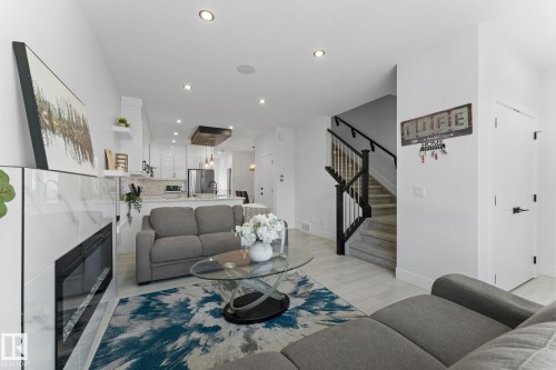 Open-concept living area featuring a modern fireplace with a tiled surround, recessed lighting, and light wood-finish flooring - 3606 42 Avenue, Beaumont, AB 