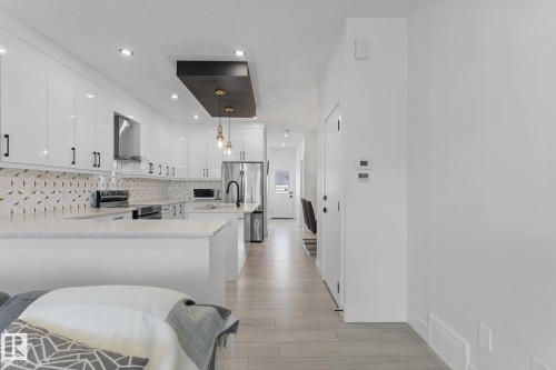 Modern kitchen featuring white high-gloss cabinetry, quartz countertops, a patterned tile backsplash, recessed lighting, and stainless steel appliances - 3606 42 Avenue, Beaumont, AB 