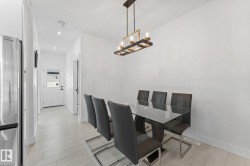 Dining area featuring a modern linear chandelier, light wood-finish flooring, and recessed lighting - 