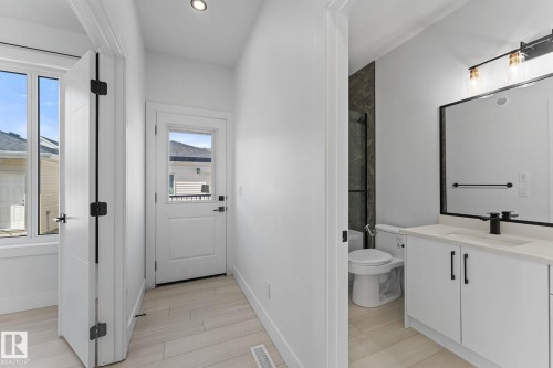 Modern bathroom featuring a single vanity with quartz-style countertop, matte black faucet, and a framed mirror - 3606 42 Avenue, Beaumont, AB 