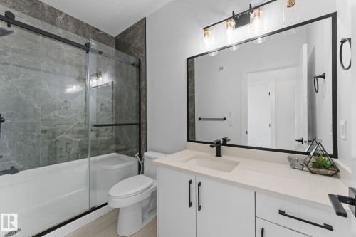 Bathroom featuring a white vanity with a light-toned countertop, a black-framed mirror, and a wall-mounted light fixture - 3606 42 Avenue, Beaumont, AB 