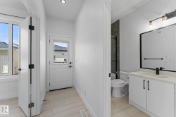 Modern bathroom featuring a single vanity with quartz-style countertop, matte black faucet, and a framed mirror - 