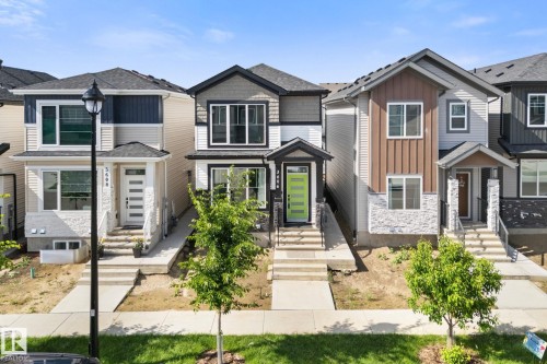 Modern home with a striking lime green front door, featuring a covered entry, dark trim windows, and mixed siding with stone accents - 3606 42 Avenue, Beaumont, AB 