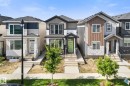Modern home with a striking lime green front door, featuring a covered entry, dark trim windows, and mixed siding with stone accents - 3606 42 Avenue, Beaumont, AB 