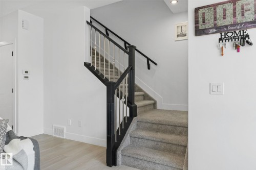 Two-tone staircase featuring black newel posts and handrails with white balusters - 3606 42 Avenue, Beaumont, AB 