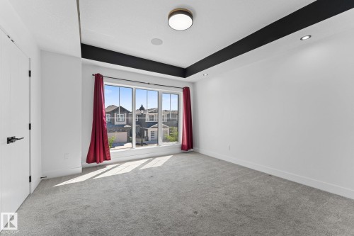 Spacious room with large multi-pane windows, a tray ceiling featuring a contrasting dark accent, recessed lighting, and a contemporary flush-mount ceiling fixture - 3606 42 Avenue, Beaumont, AB 