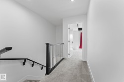 Upper-level hallway featuring light gray carpeting, crisp white walls, and recessed lighting - 