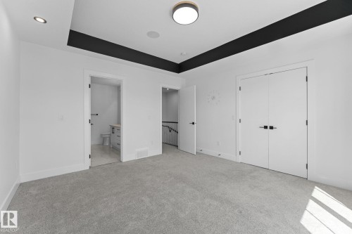 Spacious room featuring light gray carpeting, crisp white walls, and a recessed ceiling design with a dark accent - 3606 42 Avenue, Beaumont, AB 
