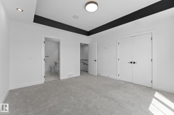 Spacious room featuring light gray carpeting, crisp white walls, and a recessed ceiling design with a dark accent - 