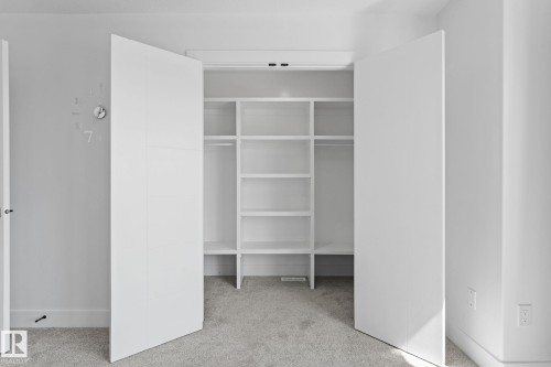 Built-in closet system featuring white shelving and hanging rods - 3606 42 Avenue, Beaumont, AB 