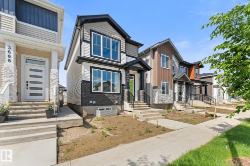 Contemporary two-story exterior featuring a prominent gabled roofline, mixed material facade with horizontal siding and stone accents, a covered front entry, and multiple large windows - 3606 42 Avenue, Beaumont, AB 