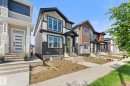 Contemporary two-story exterior featuring a prominent gabled roofline, mixed material facade with horizontal siding and stone accents, a covered front entry, and multiple large windows - 3606 42 Avenue, Beaumont, AB 