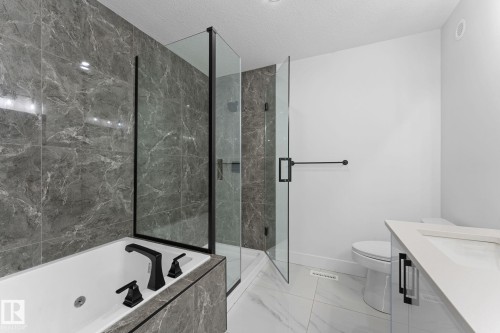 Bathroom featuring a built-in tub with matte black fixtures, a walk-in shower with clear glass enclosure, a white toilet, and a vanity with a white countertop - 3606 42 Avenue, Beaumont, AB 