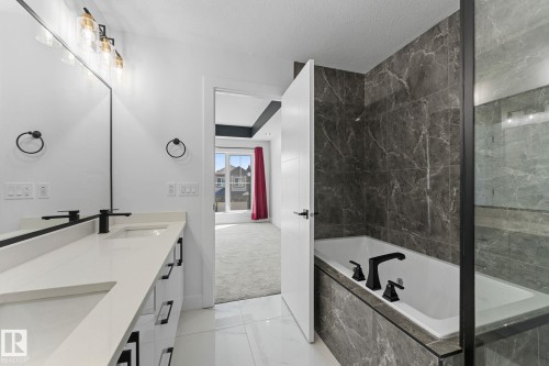 Contemporary bathroom featuring a dual vanity with white countertops, integrated sinks, and matte black faucets - 3606 42 Avenue, Beaumont, AB 