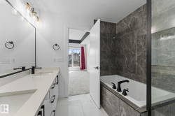 Contemporary bathroom featuring a dual vanity with white countertops, integrated sinks, and matte black faucets - 