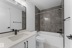 Bathroom featuring a white vanity with a light-toned countertop, an undermount sink, and a matte black faucet - 