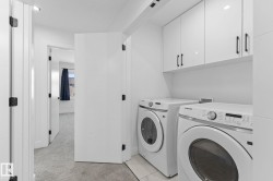 Dedicated laundry area featuring white gloss cabinetry with dark hardware, white tile flooring, and recessed lighting - 
