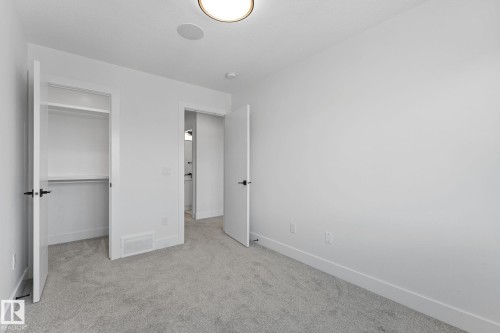 Bright room featuring light gray carpet, white walls, and a built-in closet with shelving - 3606 42 Avenue, Beaumont, AB 