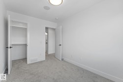 Bright room featuring light gray carpet, white walls, and a built-in closet with shelving - 