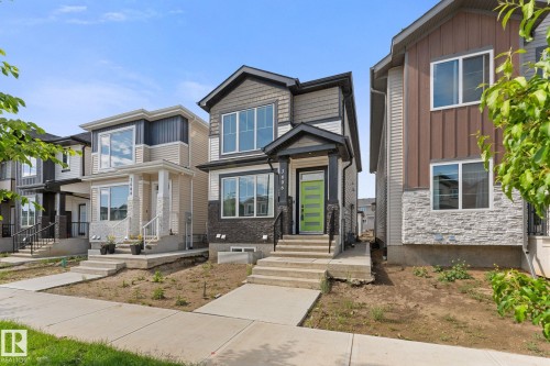 Contemporary exterior featuring a bright green front door, multi-toned siding, stone veneer accents, and an integrated porch - 3606 42 Avenue, Beaumont, AB 