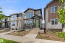 Contemporary exterior featuring a bright green front door, multi-toned siding, stone veneer accents, and an integrated porch - 3606 42 Avenue, Beaumont, AB 