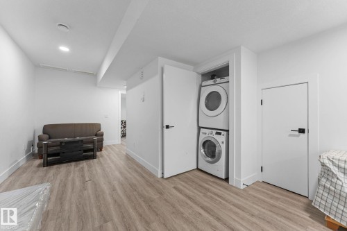 Laundry closet with stacked appliances, light wood-finish flooring, recessed lighting, and white walls - 3606 42 Avenue, Beaumont, AB 