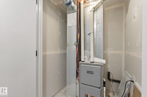 Utility closet featuring a furnace with visible ductwork and piping, drywall-finished walls, and a white interior door - 3606 42 Avenue, Beaumont, AB 