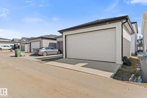 Detached garage structure featuring white panel siding, a white overhead door, and a concrete driveway apron - 3606 42 Avenue, Beaumont, AB 