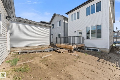 Rear exterior featuring a wooden deck with black metal railings, white horizontal siding, large windows, and a basement window - 3606 42 Avenue, Beaumont, AB 