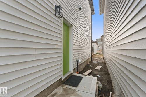 White siding exterior with a vibrant green door - 3606 42 Avenue, Beaumont, AB 