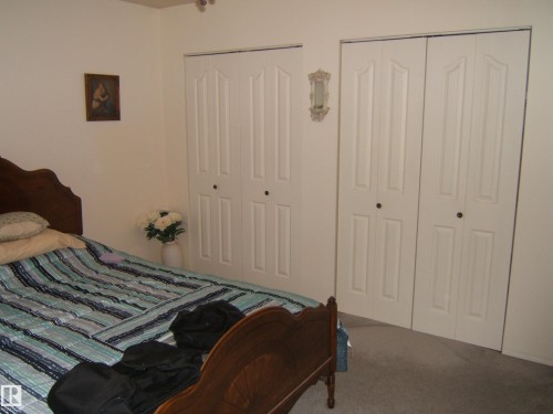 White paneled bi-fold doors, neutral wall paint, and gray carpeted flooring - 4606 51 Avenue, Two Hills, AB 