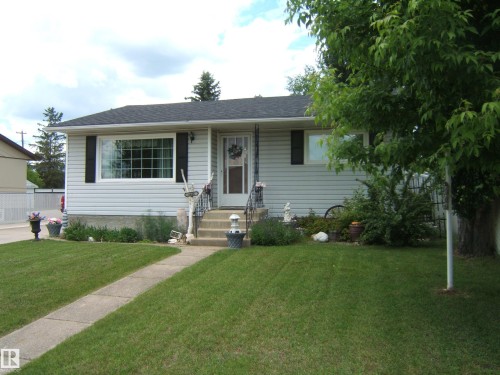 Single-story residence featuring light gray siding, a dark shingled roof, and black shutters - 4606 51 Avenue, Two Hills, AB 