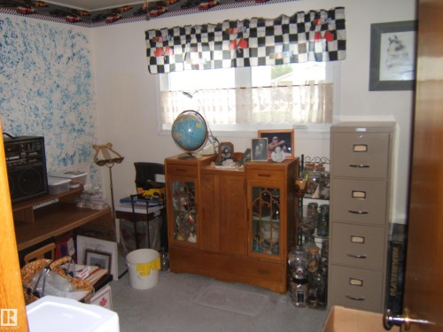 Room featuring a window with natural light, a wood-finish desk, and carpeting - 4606 51 Avenue, Two Hills, AB 
