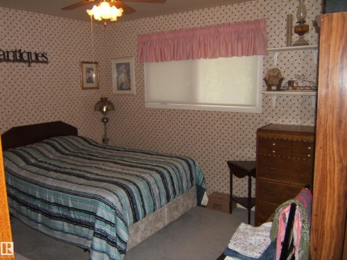 Room featuring patterned wallpaper, carpeted flooring, and a ceiling fan with integrated lighting - 4606 51 Avenue, Two Hills, AB 
