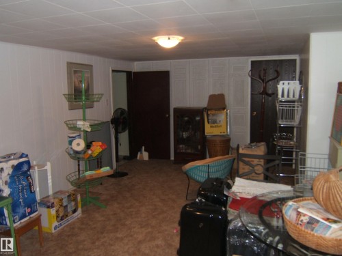 Carpeted room featuring white paneled walls and a drop ceiling with recessed lighting - 4606 51 Avenue, Two Hills, AB 