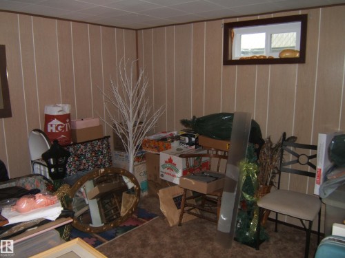 Room featuring vertical paneling, a recessed window with wood trim, and a drop ceiling - 4606 51 Avenue, Two Hills, AB 