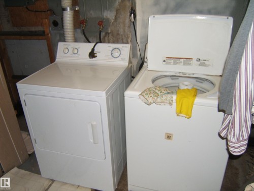 Dedicated laundry area featuring a white top-load washing machine and a white front-load dryer - 4606 51 Avenue, Two Hills, AB 