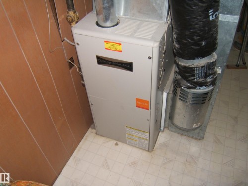 Frigidaire furnace unit featuring metal ductwork and adjacent paneling - 4606 51 Avenue, Two Hills, AB 