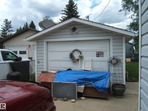 Detached garage structure featuring light-colored horizontal siding and a white garage door - 4606 51 Avenue, Two Hills, AB 
