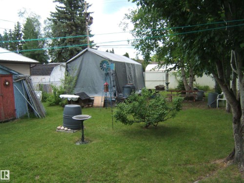 Expansive green lawn with mature trees and a large, covered outbuilding - 4606 51 Avenue, Two Hills, AB 