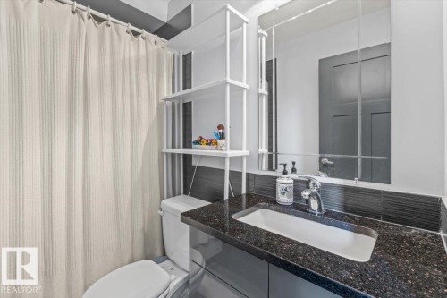 Bathroom vanity with an integrated sink and speckled dark countertop - 3 7210 96 Street, Edmonton, AB - Indoor Photo Showing Bathroom
