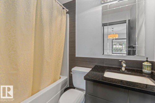 Bathroom featuring a vanity with a dark speckled countertop, an undermount sink, and chrome faucet - 3 7210 96 Street, Edmonton, AB - Indoor Photo Showing Bathroom