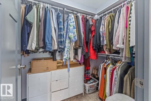 Corner walk-in closet featuring white built-in drawer storage and multiple hanging rods - 3 7210 96 Street, Edmonton, AB - Indoor With Storage