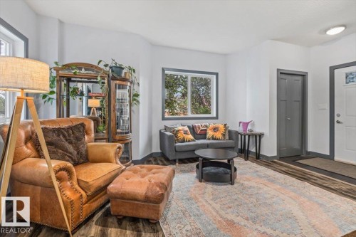 Living area featuring ample natural light, wood-finish flooring, white walls, and dark trim - 3 7210 96 Street, Edmonton, AB - Indoor Photo Showing Living Room