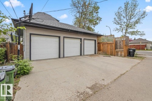 Detached three-car garage featuring panel-style doors, horizontal siding, and a gabled roofline - 3 7210 96 Street, Edmonton, AB - Outdoor